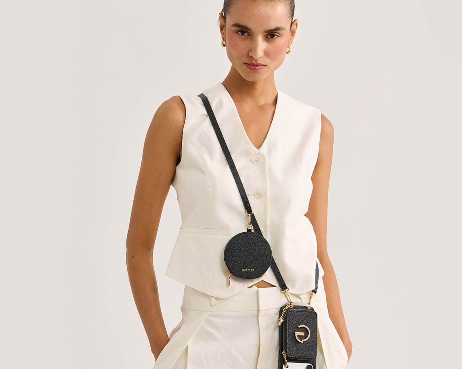 Model wearing a black Custype crossbody wallet phone case with a round pouch